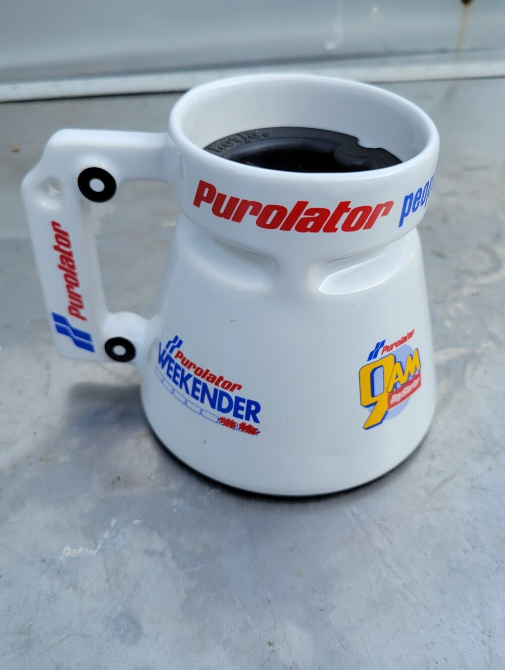 Vintage ceramic travel mug with a white finish and Purolator branding. This mug